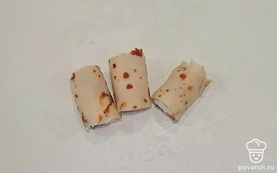 Блинные рулетики превратите в роллы с помощью острого ножа, уложив их на деревянную доску.