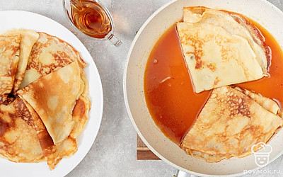 В сковороду с соусом выложите блинчики, сложенные треугольниками. Когда одна сторона блинчиков напитается сиропом, переверните их на другую и добавьте оставшееся сливочное масло, и увеличьте огонь. Когда сироп начнет активно кипеть, влейте алкоголь и подожгите. Снимите блинчики на тарелку, полейте соусом и присыпьте цедрой апельсина.