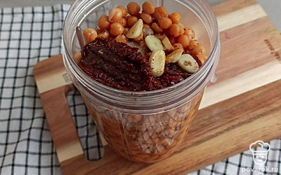 Загрузите в блендер нут, вяленые помидоры и чеснок и измельчите до состояния пасты. Переложите паштет в другую емкость.