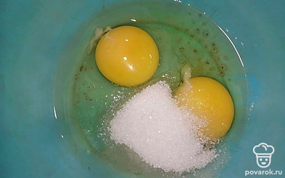 В глубокую миску вбейте яйца. Засыпьте сахар и с помощью венчика взбейте смесь.