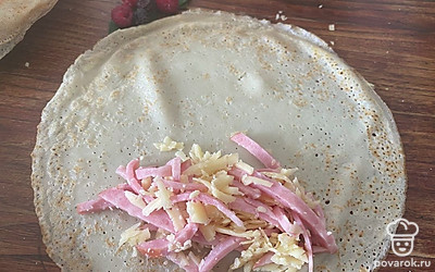 Блин положить на большую тарелку и выложить начинку. Завернуть блин, чтобы получился конвертик.