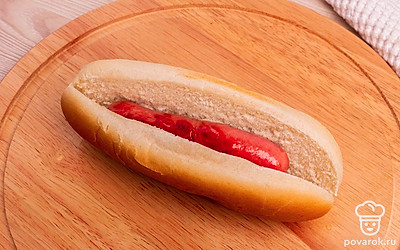 Возьмите булочку для хот-дога, разрежьте ее вдоль по центру, но не до конца. Положите в булочку сосиску.