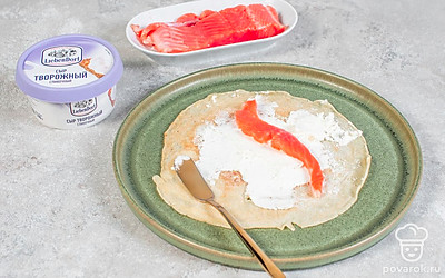 Добавьте в блинчики начинку. Каждый блин смажьте тонким слоем сыра. Семгу нарежьте полосками. На каждый блин выложите по полоске рыбы и сверните блинчики в рулет. Нарежьте каждый рулет на 2-3 части, чтобы был виден красивый срез.