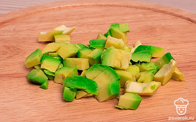 На разделочной доске нарежьте кубиками среднего размера очищенное авокадо и репчатый лук.