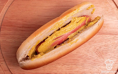 Возьмите булочку для хот-дога, разрежьте ее вдоль по центру, но не до конца. Положите в булочку сосиску и смажьте горчичным соусом.