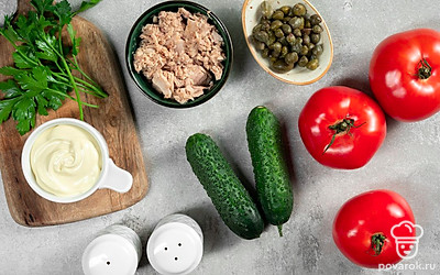 Подготовьте продукты для закуски. Слейте с рыбы масло. Петрушку измельчите. Огурец очистите от кожуры, нарежьте мелкими кубиками. Помидоры ополосните.