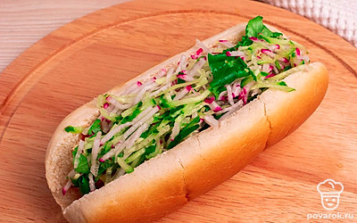 Положите в центр обжаренную сосиску и заполните хот-дог начинкой из овощей и зелени. Положите хот-дог на тарелку и отправьте в микроволновую печь на 1 минуту. Выставите мощность 600 Вт.