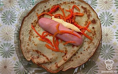 Сосиски отварить в кипящей воде пару минут. В блин завернуть сосиску, корейскую морковь и немного сырного соуса.