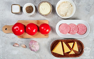 Подготовьте продукты для закуски. Помидоры помойте, обсушите. Колбасу нарежьте мелко кубиком. Сыр натрите на средней терке. Измельчите укроп. Чеснок мелко порубите.