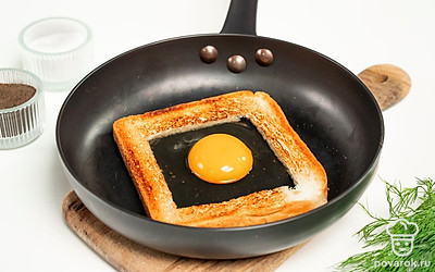 Подготовьте хлеб. В куске тоста вырежьте сердцевину. Сделайте отверстие достаточно большим, иначе яйцо вытечет или будет жариться дольше. Этот ломтик и вырезанную сердцевину подсушите на сковороде с одной стороны.