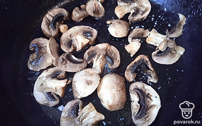 На сковороде с разогретым растительным маслом обжарьте нарезанные шампиньоны с одной стороны 1 минуту.