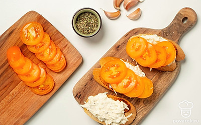 Сформируйте тосты. В миске смешайте тертый сыр, измельченный чеснок, майонез и прованские травы. На хрустящий тост выложите ложку сырно-майонезной массы, сверху кусочек помидора. Слегка придавите. Таким образом распределите начинку на все тосты.