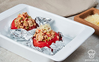 Сделайте блюдо. Включите духовку на 180 градусов. С помидоров срежьте «крышечки» и выньте мякоть. Вложите в овощи готовую начинку. Сверху на каждый помидор натрите сыр. В форму для выпечки постелите фольгу, смажьте оставшимся маслом. Выложите помидоры в форму, накройте срезанными «крышечками» и отправьте выпекаться на 20 минут.