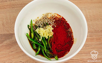 В подходящей по размеру емкости смешайте нарезанный перец, кунжут, чеснок, специи и соевый соус. Смешайте до однородности.