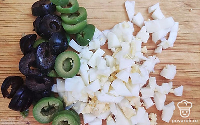 Нарежьте яйца на кубики или натрите на крупной терке. Оливки и маслины нарежьте кольцами.