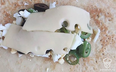 На блинчик намажьте соус. Сверху выложите перемешанные яйца с маслинами и оливками. Выложите ломтики сыра. Сверните конвертиком и обжарьте на сковородке с двух сторон по одной минуте.