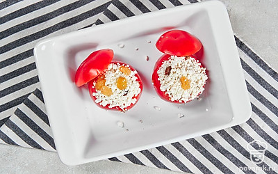 Сделайте блюдо. Включите духовку на 180 градусов. С помидоров срежьте верхушки. С помощью чайной ложки выньте мякоть. Заполните помидорки творогом, сверху полейте сметаной. Закройте верхушками. Форму для выпечки смажьте маслом, выложите помидоры и отправьте их запекаться на 10 минут.