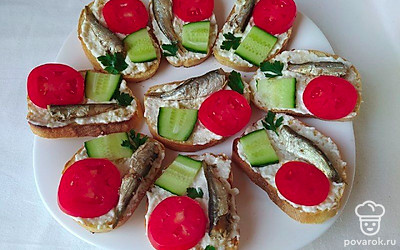 Огурцы и помидоры нарежьте тонкими кусочками, выложите по одному на каждый ломтик гренки. Из шпротов слейте масло. Выложите по одной рыбке на каждую гренку. Блюдо готово.