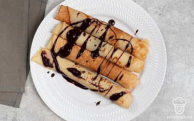 Разложите блины по красивым тарелкам. Полейте их растопленным шоколадом и подайте на завтрак. 