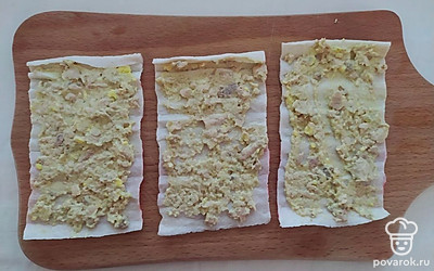 Разверните крабовые палочки на ровной поверхности. Выложите небольшое количество начинки на крабовую основу и равномерно распределите ее по всей поверхности.