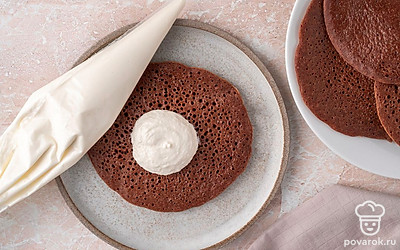 Переложите крем в кондитерский мешок и отсадите его по центру всех блинчиков с непрожаренной стороны. Оставьте немного крема в мешке.