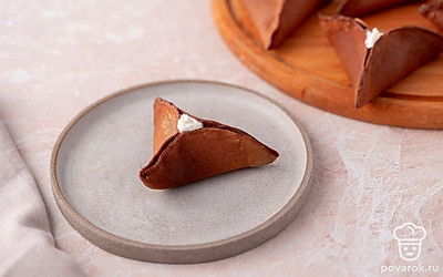 Разложите блинчики-треугольники на блюде и украсьте каждый из них небольшой каплей крема в месте отверстия. 