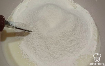 Добавьте просеянную муку и хорошо перемешайте до однородной массы, чтобы не было комочков.
