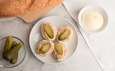 Полученную смесь выложите в готовые половинки яичного белка. Фаршированные яйца печеночным паштетом выложите на тарелку и украсьте маринованными огурцами. Приятного аппетита!