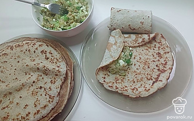 На светлую сторону расправленного блина выложите 1 ложку начинки, заверните по краям и сверните в плоский рулетик.