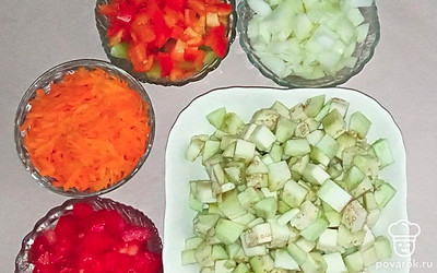 Измельчите овощи: морковь натрите на крупной терке, баклажаны, перец порежьте на маленькие кубики, лук и помидоры нарежьте произвольно, а острый перец накромсайте на мелкие кусочки.