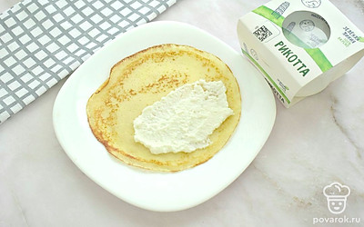 Смажьте сковороду маслом один раз и оптимально нагрейте поверхность. Жарьте тонкие блинчики примерно по 1 минуте с каждой стороны (получится 9 маленьких блинчиков). Рикотту смешайте со столовой ложкой сахара и сметаной. Начинку из рикотты выложите на половину блинчика, сверните. Начините все блины.