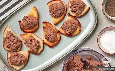 Сделайте тосты. Ломтики хлеба отправьте в тостер и обжарьте до хрустящей корочки. Поджаренные кусочки хлеба смажьте толстым слоем паштета из свиной печени.