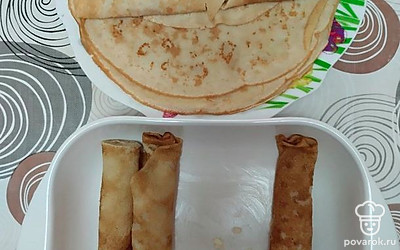 Готовые блинчики сверните в трубочку, разрежьте пополам и плотно выложите в форму для запекания.