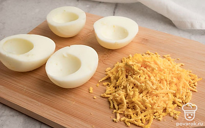 Вареные яйца очистите от скорлупы, разрежьте пополам и извлеките желтки. Натрите желтки на мелкой терке.