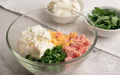 Измельчите петрушку. В подходящую по размеру емкость выложите желтки, копченую горбушу и петрушку. Добавьте творожный сыр и смешайте до однородной массы.