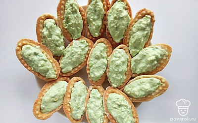 Возьмите небольшую ложку и начините каждую тарталетку полученной смесью. Достаньте семгу из морозильной камеры, она должна стать более плотной, и нарежьте ее на тонкие ломтики.