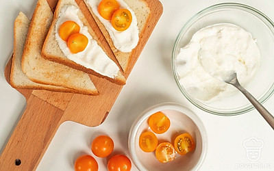 Соберите блюдо. Готовую сырную массу обильно распределите по поверхности хлеба. Сверху выложите половинки помидоров: по две на каждый тост.