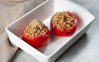 Запеките помидоры. Наполните томаты фаршем, накройте крышечками и поставьте в форму для запекания, застеленную пергаментом. Запекайте помидоры в разогретом до 180 градусов духовом шкафу в течение 20 минут.