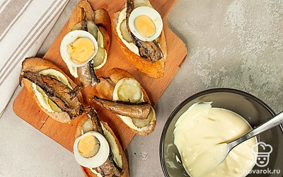 Соберите тосты. Намажьте ломтики багета намазкой, выложите по кусочку яйца, соленого огурца и одной шпроте.