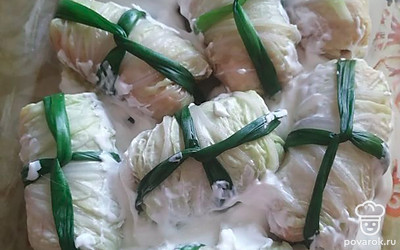 Перышки зеленого лука опустить в кипящую воду на 10 секунд, вынуть и обернуть ими конвертики из капусты. Выложить голубцы в смазанную сливочным маслом форму и залить сливками. Накрыть листом фольги и запекать в нагретой до 180 градусов духовке 30-35 минут.