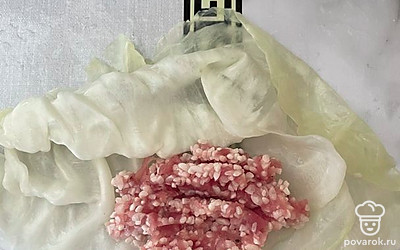 Ну подготовленные капустные листья выкладываем одну столовую ложку начинки и сворачиваем трубочкой. Подгибаем боковые края внутрь.