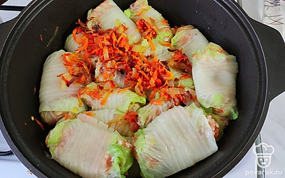 Укладывайте голубцы в жаровню плотно друг к другу. Добавьте вторую часть овощной зажарки.