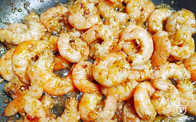 Разогрейте сковороду на среднем огне и смажьте ее маслом. Выложите креветок и обжарьте с каждой стороны до того момента, когда креветки свернуться. Добавьте к креветкам нарезанный чеснок и обжаривайте до его золотистости.