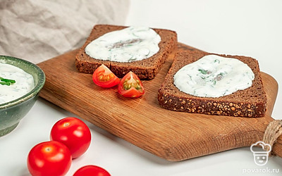 Приготовьте тосты. Смешайте сметану с зеленью, солью и чесноком. На готовые тосты намажьте соус из сметаны и зелени. Поверх него произвольно выложите дольки помидоров черри.