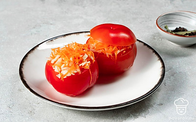 Нафаршируйте помидоры. Соедините нашинкованную капусту с морковкой и чесночной массой, хорошо перемешайте, разложите начинку по помидорам и накройте их крышечками. В контейнер поместите листик лаврушки, горошины перца и нафаршированные помидоры.