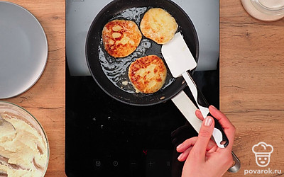 Разогрейте на сковороде масло на среднем огне. Очень важно это делать именно на среднем огне, чтобы сырники не подгорели и не растеклись. Положите в сковороду приплюснутые шарики и жарьте с каждой стороны по 3-4 минуты. Они должны получиться румяными и немного золотистыми.