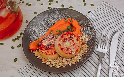 Выложите сырники на порционные тарелки. Украсьте тарелки кусочками свежей или запеченной тыквы, тыквенными семечками и овсяными хлопьями.