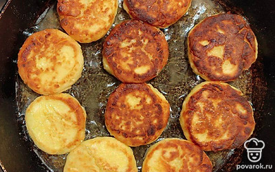 Готовые сырники подайте на блюдце теплыми. По желанию присыпьте их сахарной пудрой. Положите несколько ягод, листики мяты. Поставьте пиалу с медом.