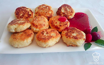 Выложите сырники на отдельную плоскую тарелку. Сверху украсьте ягодами и налейте немного варенья.