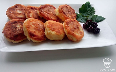 Разместите сырники на тарелке и посыпьте их ягодами.